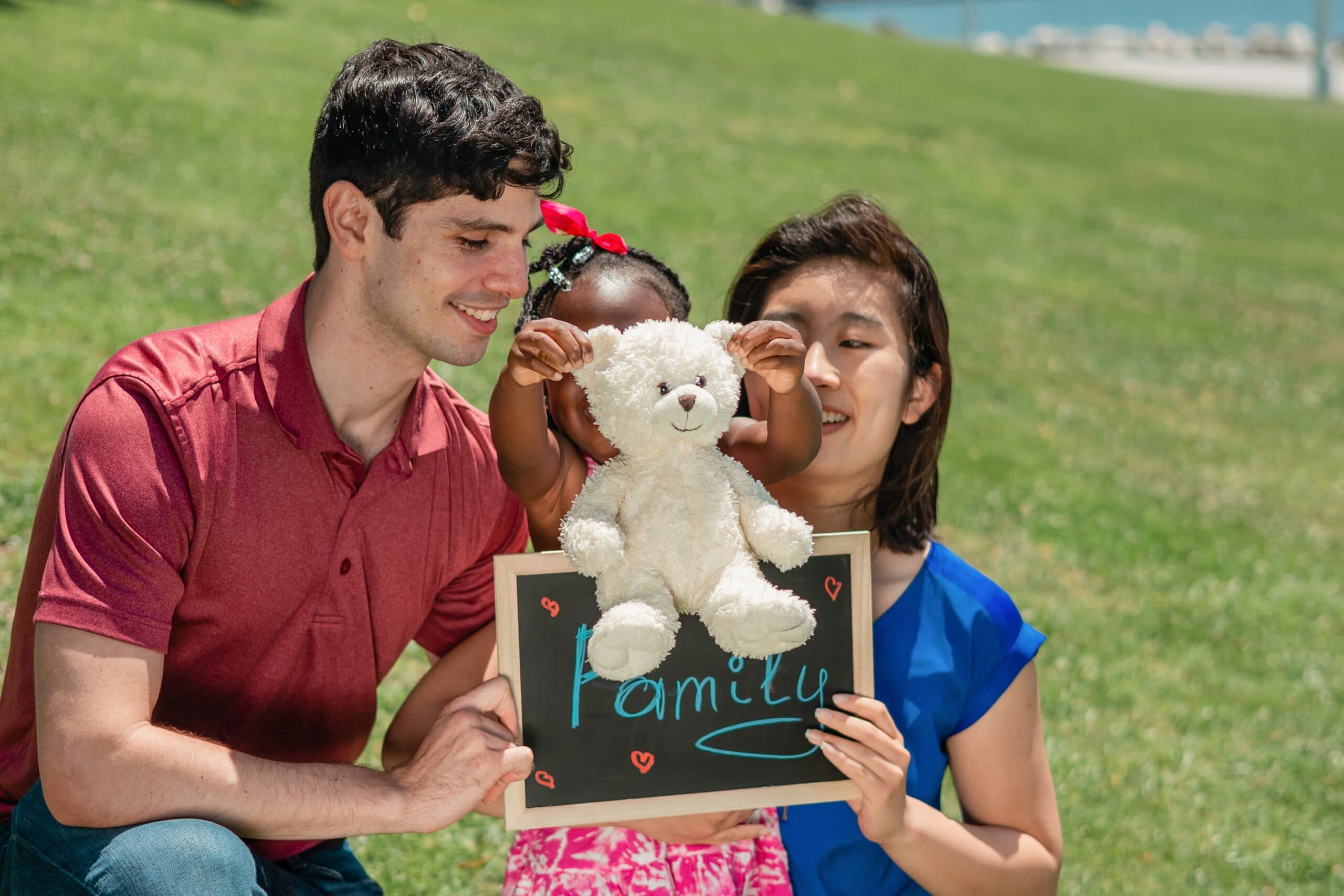 A family on a lawn holding a chalkboard that reads Familia