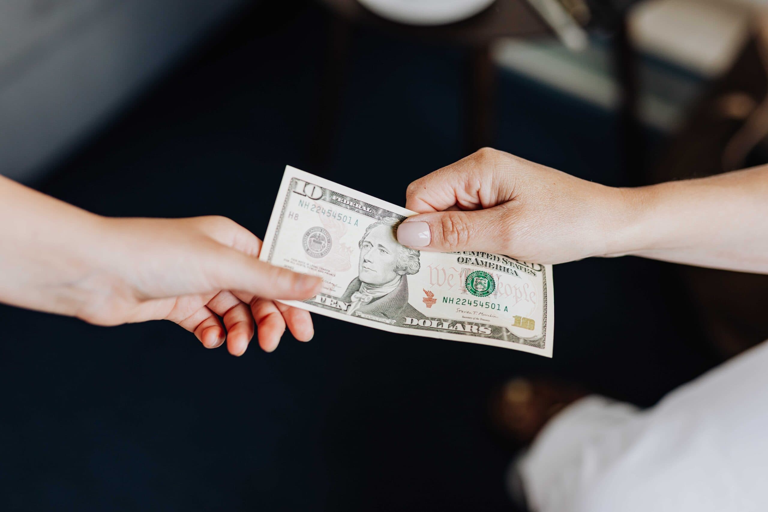 One hand passing a banknote to another